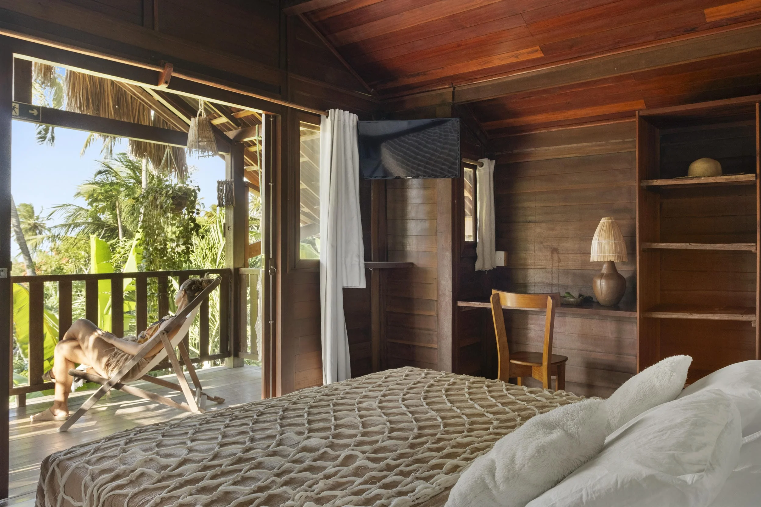 bangalo-superior-com-visao-da-cama-de-casal-biro-e-mulher-sentada-na-cadeira-da-entrada